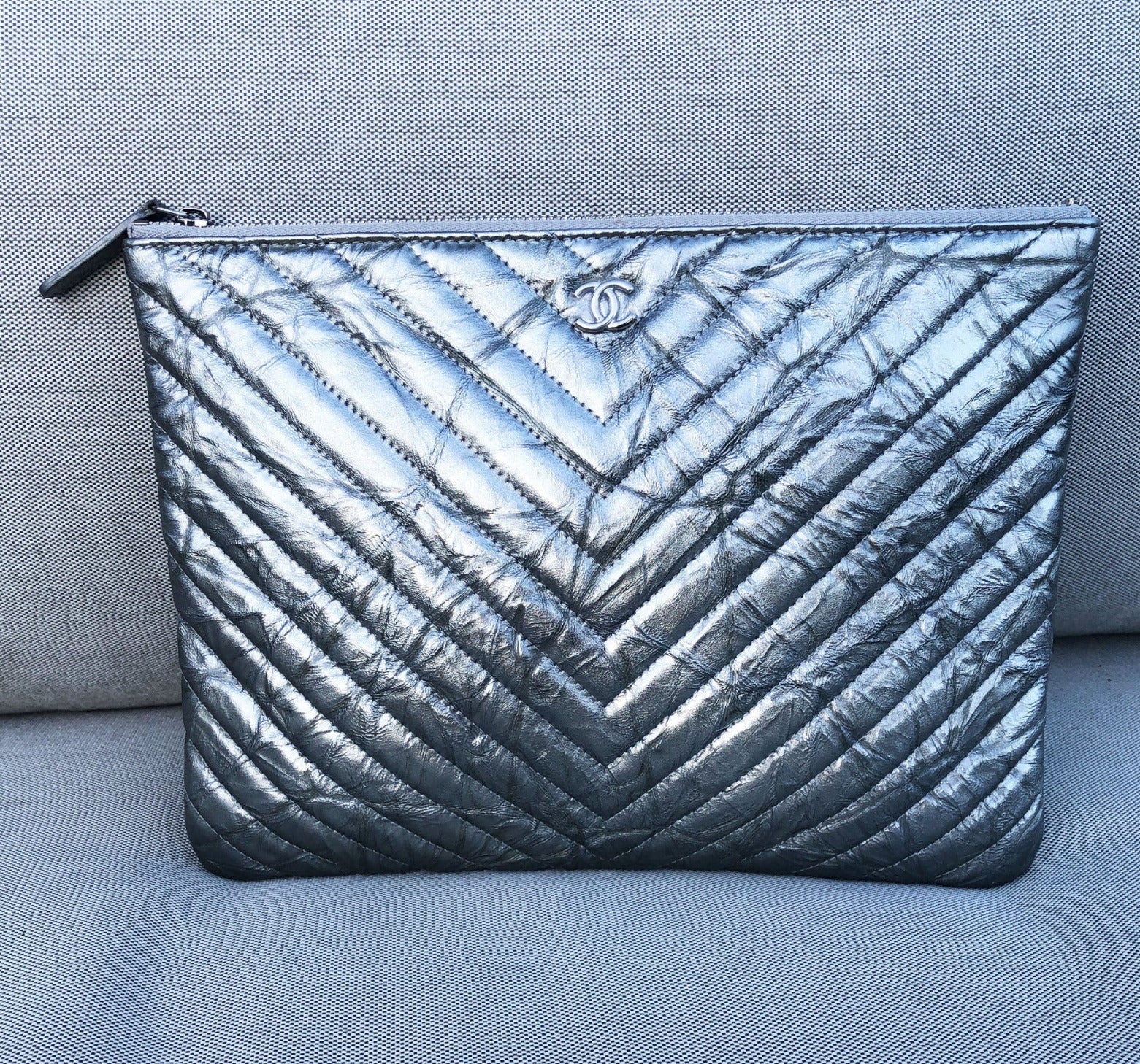 Clutch Chanel pochette O case en cuir de veau métallisé argenté chevron - Soline