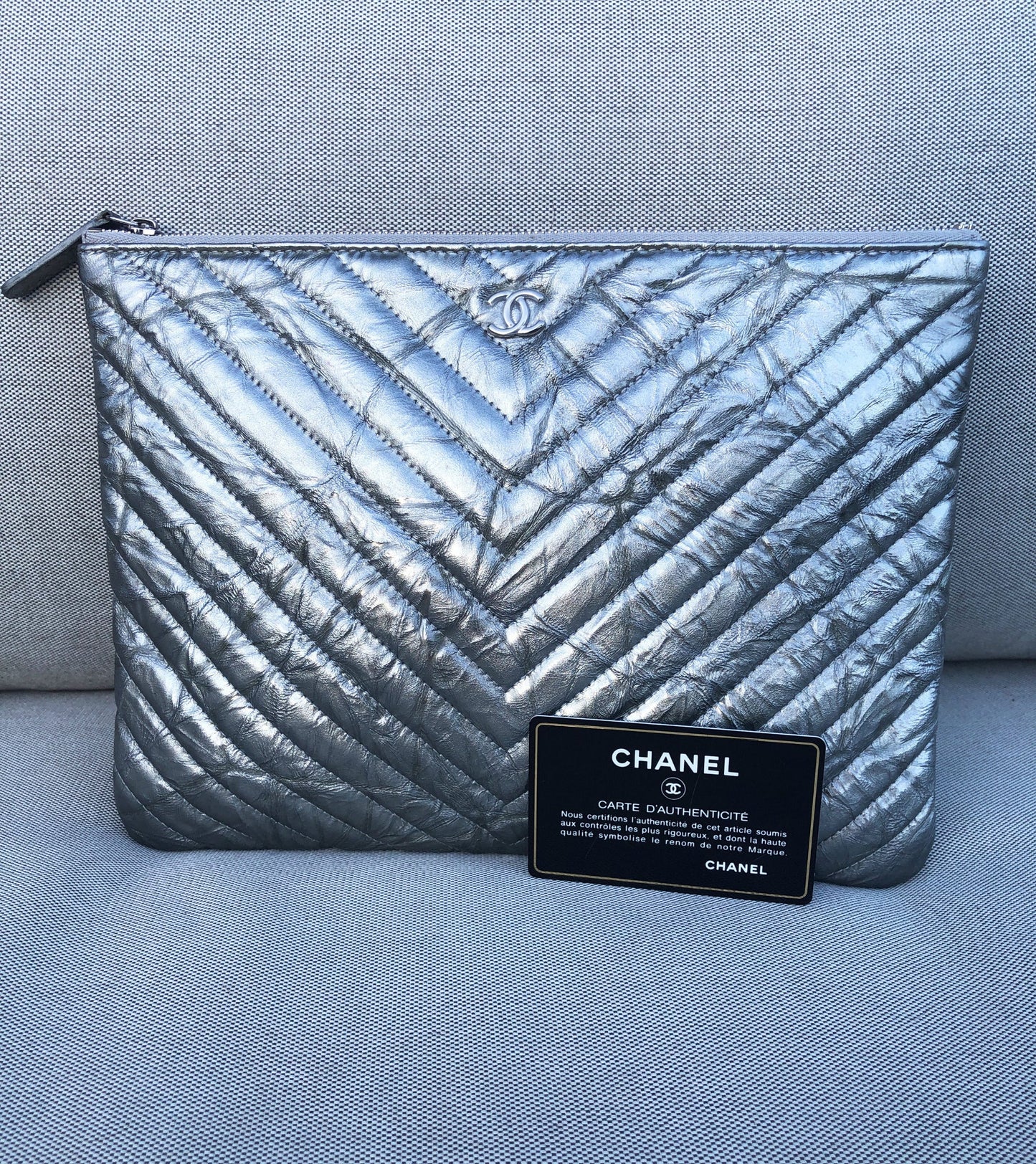 Clutch Chanel pochette O case en cuir de veau métallisé argenté chevron - Soline