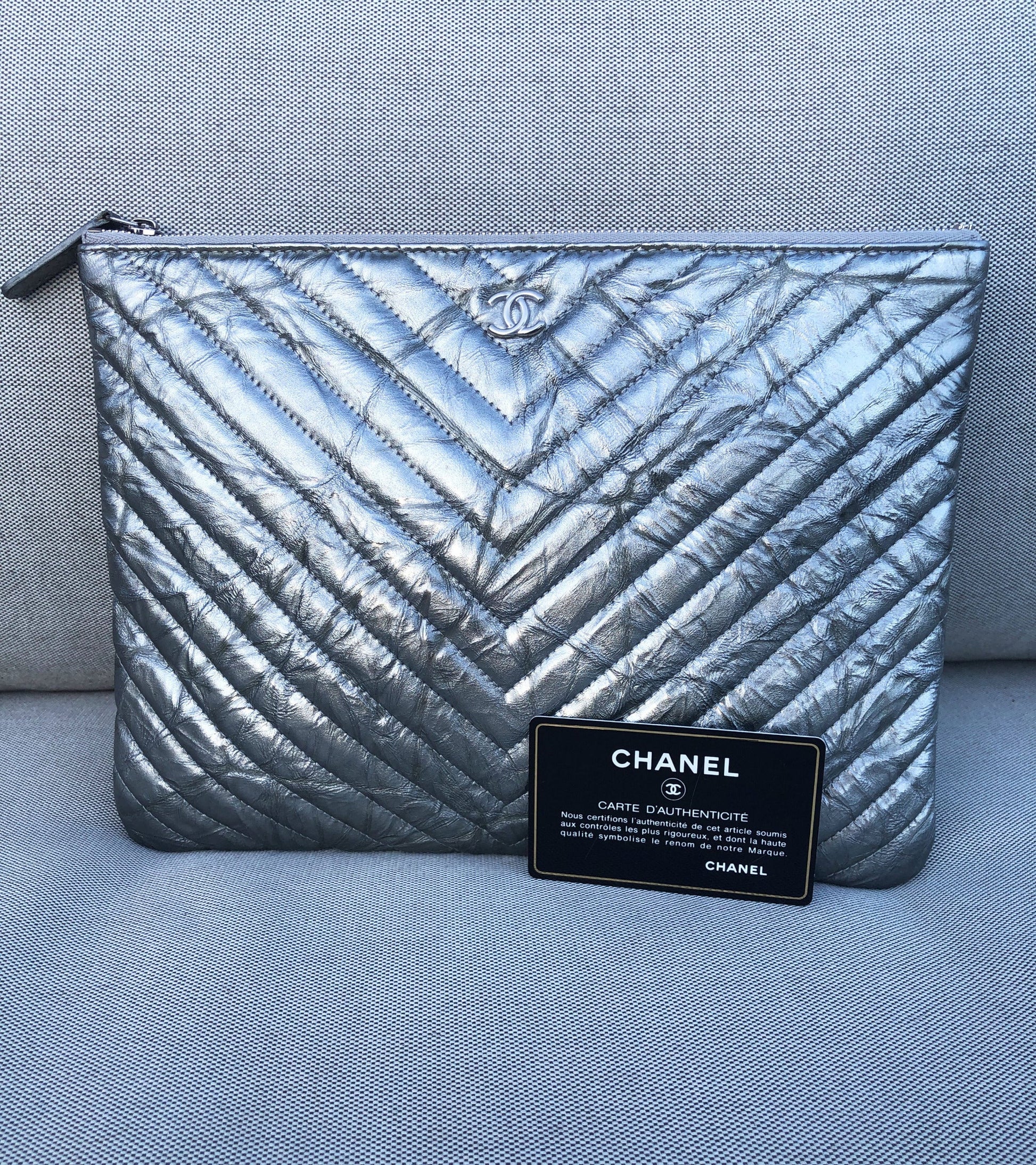 Clutch Chanel pochette O case en cuir de veau métallisé argenté chevron - Soline